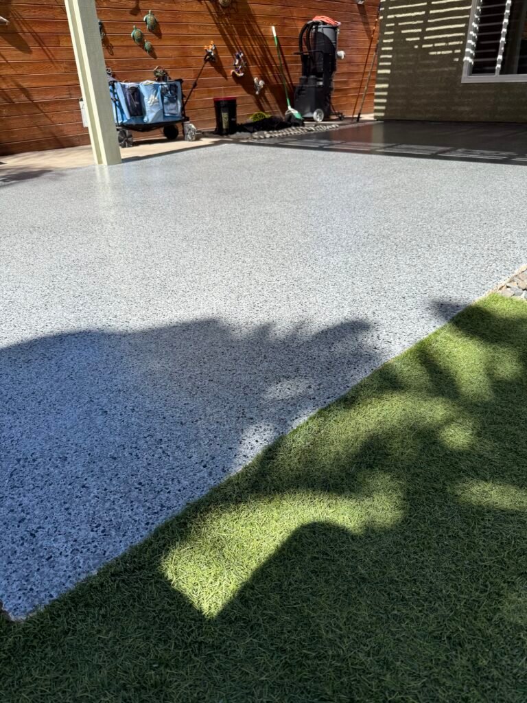Light gray decorative flake patio coating beside artificial turf