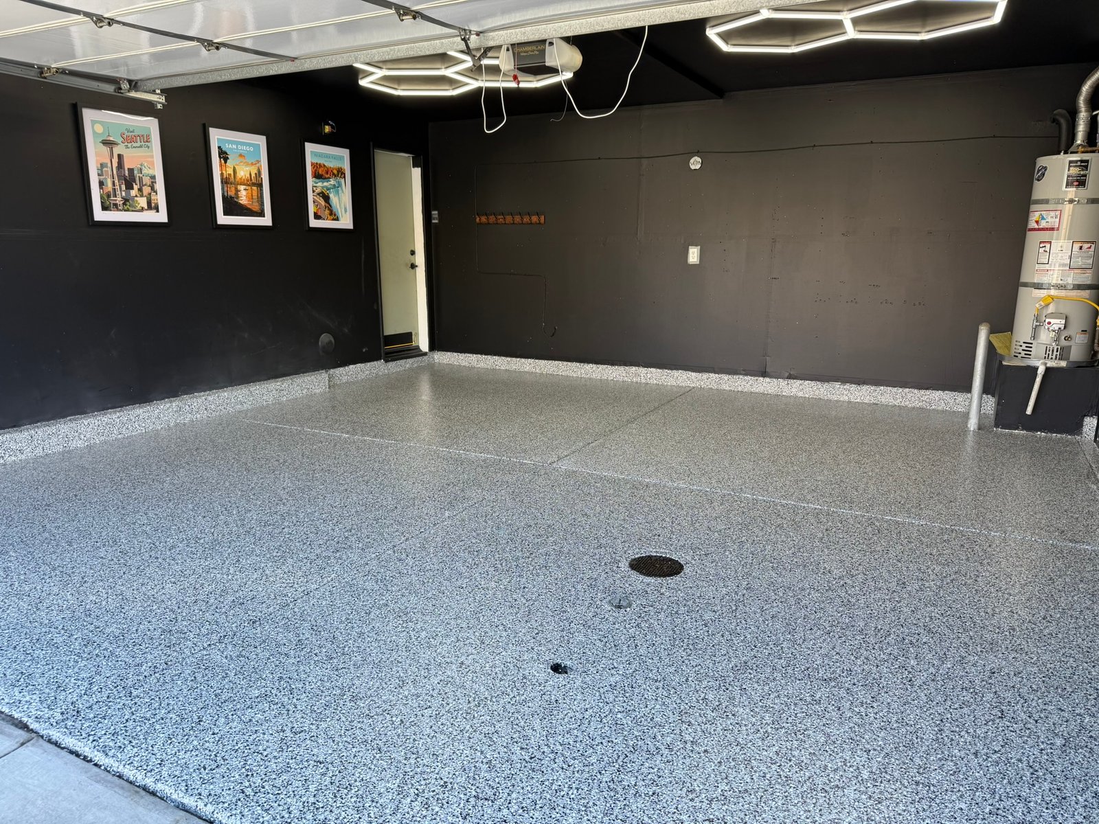 Finished Domino black, white and gray flake garage floor with black walls and overhead lighting